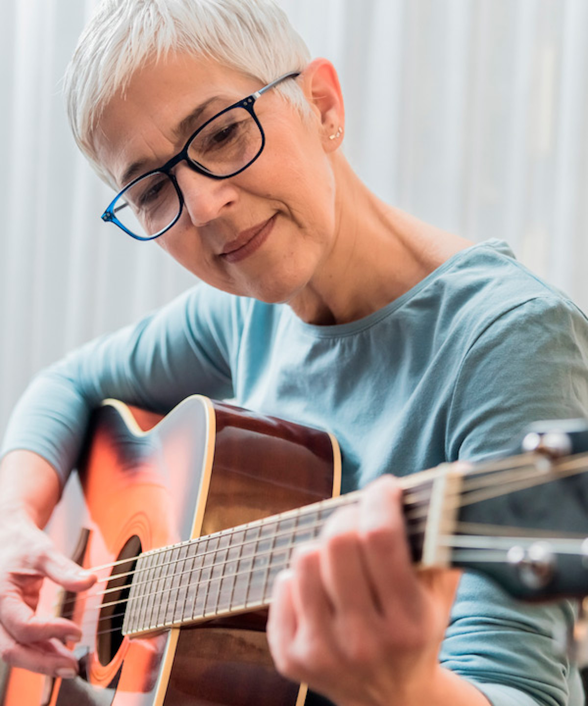 Kvinde spiller akustisk guitar med et smil